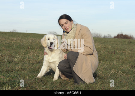 Golden Retriever (Canis lupus f. familiaris), giovane donna con cucciolo sul prato Foto Stock