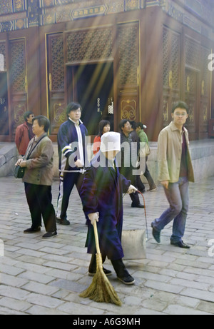 Cina Pechino cinese femmina igiene Lavoratore che indossa un mantello blu e tappo bianco spazia fino figliata in Tempio Lama Foto Stock