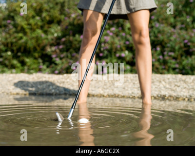 Donna giocando a golf nel flusso Foto Stock