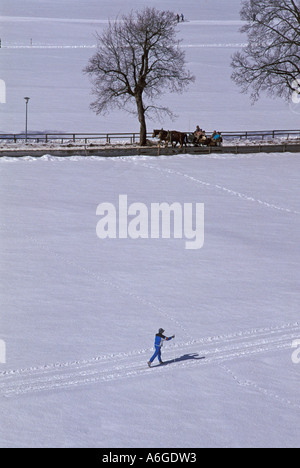 Lunga distanza sciatore e a cavallo il pullman nella coperta di neve paesaggio invernale; vicino a Oberstdorf, Algovia, Baviera, Germania Foto Stock