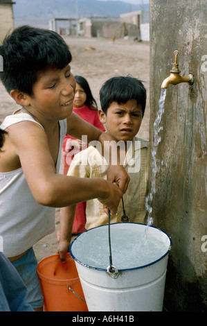 I bambini di ottenere acqua a rubinetto pubblico in corrispondenza di una baraccopoli che sono chiamati pueblos jovenes nella periferia di Lima Peru Foto Stock