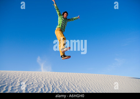 young man caught in mid leap over sand dunes Foto Stock