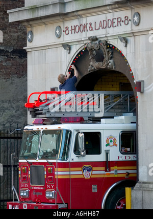 Fireman decorare un firehouse per Natale Foto Stock