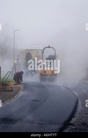 Pista la posa di asfalto in una nebbiosa mattina Foto Stock