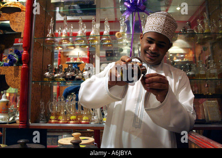 Nizwa, Oman, un perfumier colata di profumo in una bottiglia di vetro in un famoso negozio Foto Stock