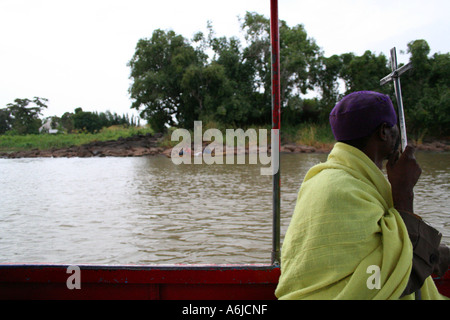 Un sacerdote frizioni crocifisso il suo personale su una barca di lasciare uno dei monasteri dell'isola nel Lago Tana, Bahar Dar, Etiopia Foto Stock