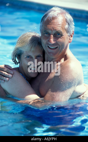 Ritratto felice coppia matura abbracciando nella piscina esterna Foto Stock