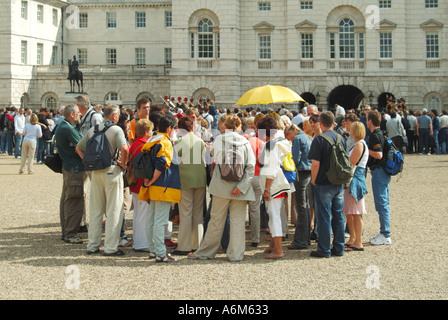 Le guardie a cavallo sfilano i turisti osservando la cerimonia del cambio della guardia, guida turistica, ombrello giallo, gruppo di persone impegnato evento Westminster, Londra, Inghilterra, Regno Unito Foto Stock
