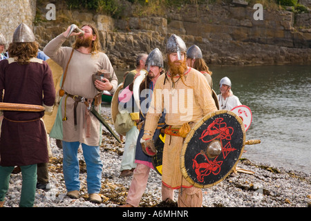 AMLWCH BIENNALE VIKING FESTIVAL attori con scudi caschi uniforme di bere da corna sulla spiaggia dopo la promulgazione della battaglia Foto Stock