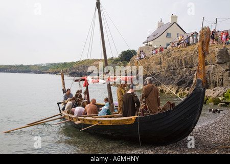 AMLWCH BIENNALE FESTIVAL VIKING Viking attori in legno barca lunga spiaggia lasciando dopo la battaglia di re promulgazione Foto Stock