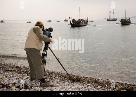 AMLWCH BIENNALE VIKING FESTIVAL fotocamera riprese uomo Viking barche lungo la spiaggia di avvicinamento per la battaglia di re promulgazione Foto Stock