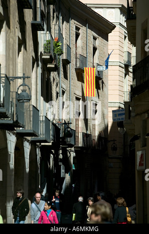 Bandiera della Catalogna (senyera) appesi in sun da un balcone in El Barri Gotic Barrio Gotico di Barcellona, persone in strada al di sotto. Foto Stock