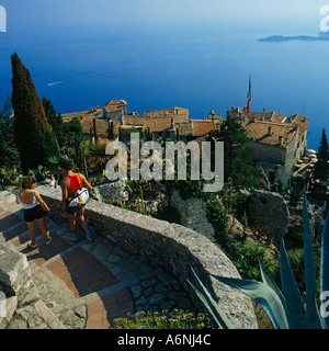 Coppia giovane camminando giù pietra ricurva fasi di antico borgo medioevale in cima alla scogliera villaggio costiero di Eze Sur Mer nel sud della Francia Foto Stock