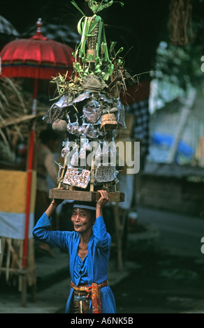 Donna Balinese arriva al tempio overladen con una gigantesca offerta religiosa luna piena celebrazioni Ubud Bali Indonesia Foto Stock