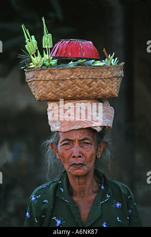 Donna Balinese arriva al tempio laden con offerte di religiosi portati sulla testa luna piena celebrazioni Ubud Bali Indonesia Foto Stock