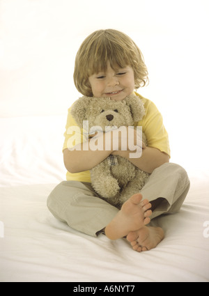 Felice ragazzo cuddling un orsacchiotto Foto Stock