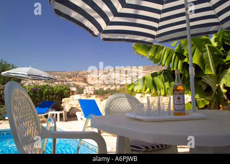 Un tavolino a bordo piscina impostazione con birra locale e la vista delle montagne sullo sfondo Foto Stock