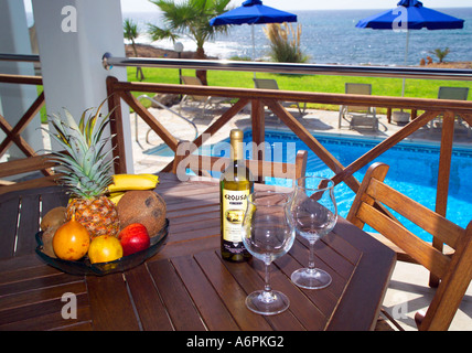 Cenare al fresco a bordo piscina su un balcone con vino e cesto di frutta a guardare il mare in Cipro Foto Stock