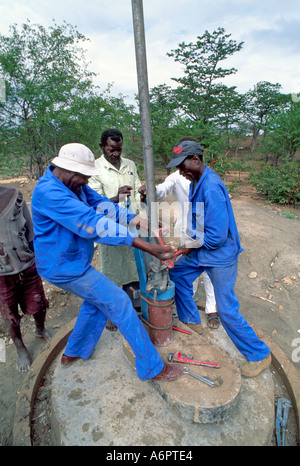 Meccanici addestrati che montano una testa della pompa a boccola. Zimbabwe Foto Stock