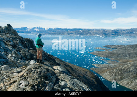 Escursionista guardando attraverso Sermilik Fjord dal Tiniteqilâq cresta est della Groenlandia Foto Stock