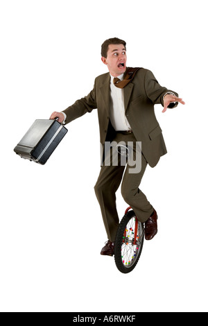 Uomo d'affari che indossa un abito marrone in equilibrio su un monociclo tenendo una valigetta guardando indietro Foto Stock