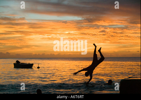 Bambini saltando in mare da un pontile sulla Funafuti isola al tramonto, Tuvalu, Pacific Foto Stock