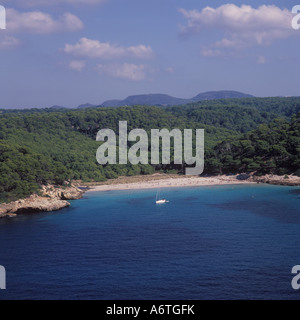 Vista aerea - yacht a vela all'ancoraggio fuori da una spiaggia remota con entroterra boscoso a est di Cala Galdana - South West Menorca / Mino Foto Stock