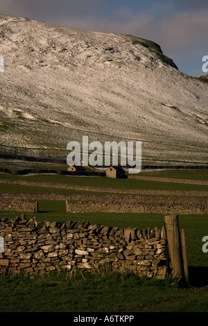 Una coppia di fienili annidato sotto una coperta di neve collina nel mezzo di righe di stalattite pareti nel villaggio di Castleton, Derbyshire. Foto Stock