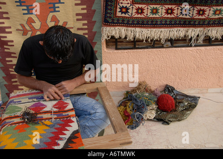 Un tessitore lavora su un tappeto tradizionale in un laboratorio di tessitura di tappeti ad Antalya in Turchia Foto Stock