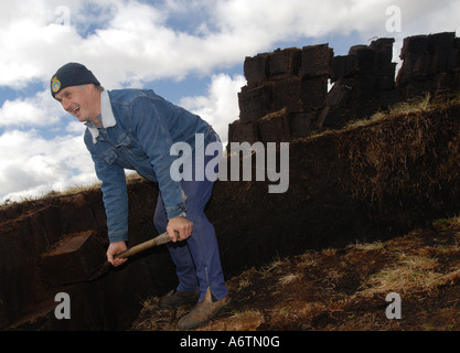 Un uomo che taglia la torba nel modo tradizionale con un spade per combustibile e composto per i centri di giardino nel Isole Falkland Foto Stock