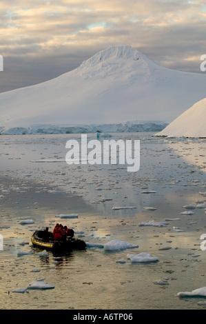 Le gamme della montagna intorno al porto Lockeroy con la luce della sera e rompere le nuvole, Zodiak nell'acqua Foto Stock