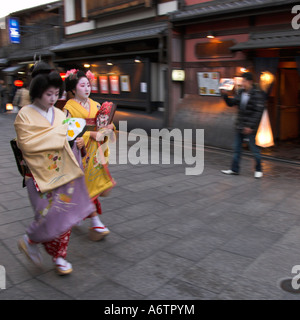 Giappone Central Honshu Kansai Kyoto quartiere di Gion Gion Corner due geishe in abito tradizionale a piedi al tramonto a loro headq Foto Stock