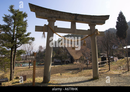 Giappone Honshu centrale quartiere di Hida Takayama Hida non Sato Hida Folk Village backlit lo Shintoismo torii con casa tradizionale bkgd Foto Stock