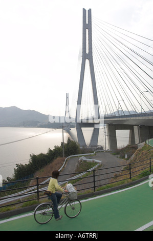 Giappone Ehime Omishima arcipelago isola ponte Tatara Honshu Shikoku bridge project Nishiseto expressway equitazione donna in bicicletta Foto Stock