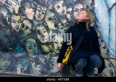 Giovane donna di fronte a Graffiti sul Muro di Berlino, East Side Gallery, Berlino, Germania Foto Stock