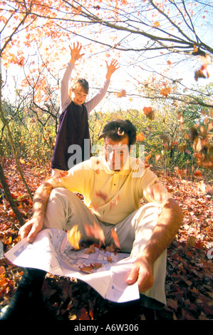 La figlia della famiglia gettando le foglie sul padre Foto Stock