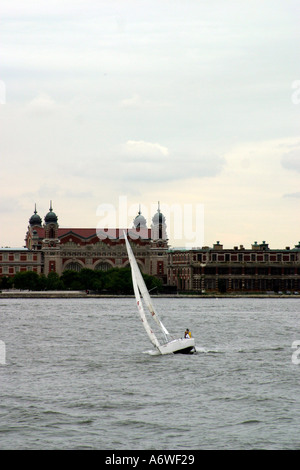 Una barca a vela chiodini di fronte l'isola di Ellis Island Foto Stock