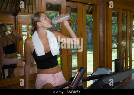Giovane donna di bere sulla cyclette in palestra Foto Stock