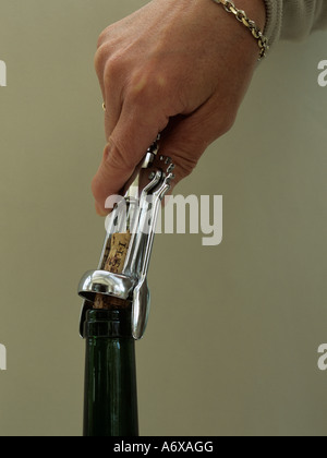 STUDIO in prossimità di una mano womans prendendo un tappo di sughero di una bottiglia di vino con un acciaio inossidabile cavatappi Foto Stock