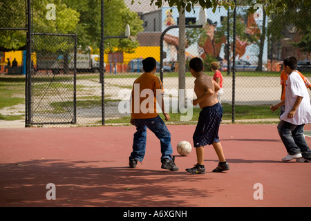 ILLINOIS Chicago Boys giocare a calcio sul campo da tennis Parco nel quartiere Pilsen Foto Stock