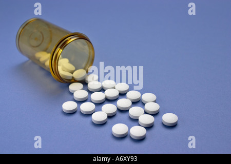 Bottiglia di prescrizione con sparsi in compresse bianche su viola Foto Stock