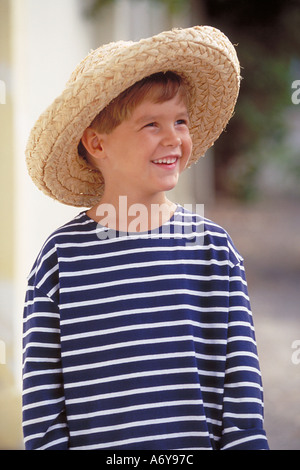 Ritratto di un ragazzo che indossa un cross-camicia a righe e un cappello di paglia Foto Stock