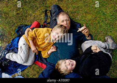 Otto e dieci anni di old boys giacente sul padre a uno spuntino durante le escursioni Foto Stock