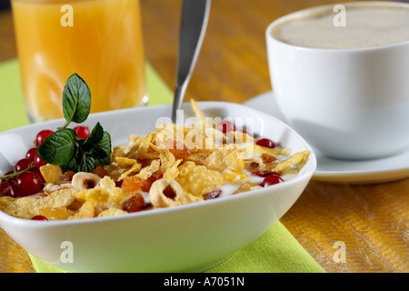 La prima colazione con caffè e latte e ciotola con fiocchi di mais di bacche e dadi Foto Stock