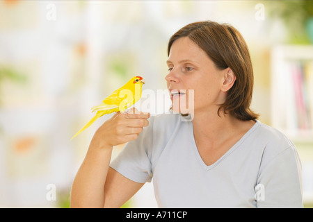 Donna con rosso fiammante parrocchetto sulla sua mano / Foto Stock