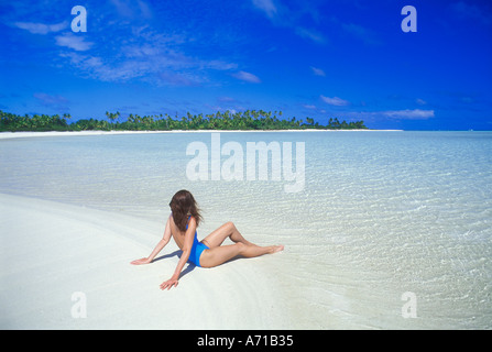 Donna in costume da bagno seduto sulla spiaggia in Laguna Aitutaki nelle isole Cook Oceano Pacifico del Sud Foto Stock