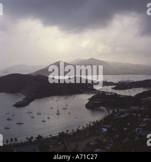 Grigio opaco nuvole formare su English Harbour e la pioggia è caduta su lontane colline con cielo tempestoso Antigua nei Caraibi Foto Stock