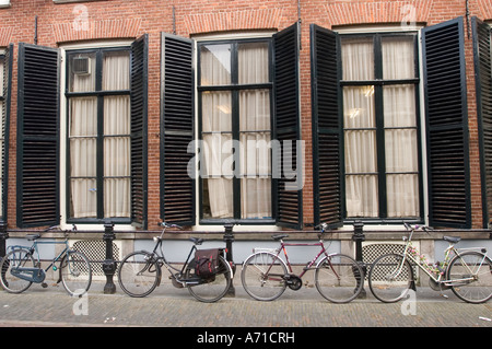 Grandi finestrini neri con tapparelle per parcheggiare le biciclette a Utrecht, Olanda. Architettura tradizionale olandese con pareti in mattoni e biciclette parcheggiate sulla strada. Foto Stock