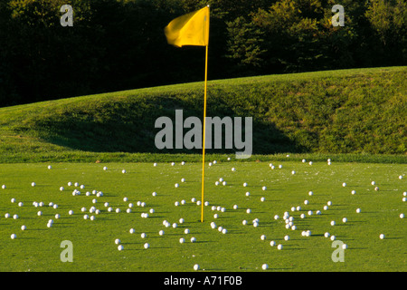 Punteggi di bianco palline da golf su un campo da golf green una bandiera gialla su un polo gialla segna il foro Foto Stock