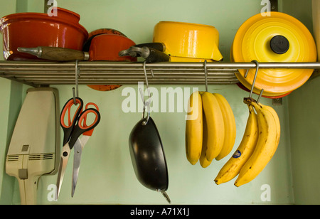 Utensili da cucina e le banane appeso dal rack Foto Stock